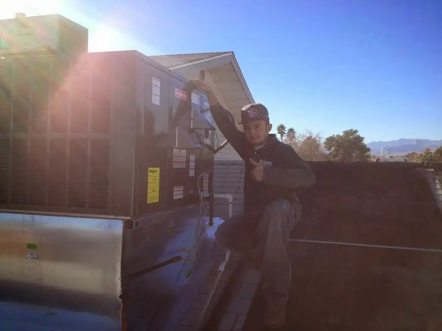 HVAC technician performing AC Tune-Up on a rooftop unit in Bay St. Louis